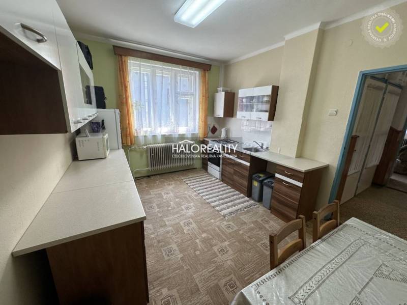 Kitchen in a family house with a dining table, cabinets, and a large window.