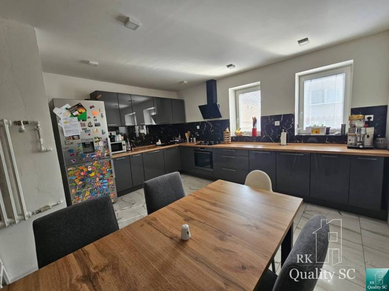 A kitchen in a family house with dark cabinets, a wooden table, and a refrigerator full of magnets.