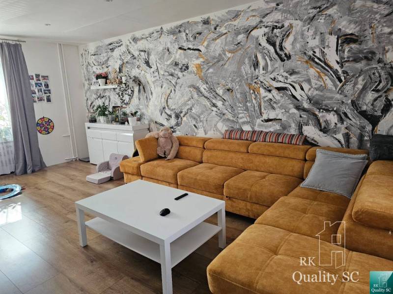 Living room in a family house with a yellow sofa and an abstract wall with colorful strokes.