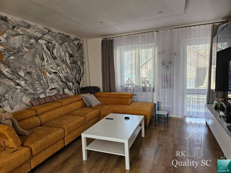 Living room in a family house with a large sofa, art on the wall, and a coffee table.