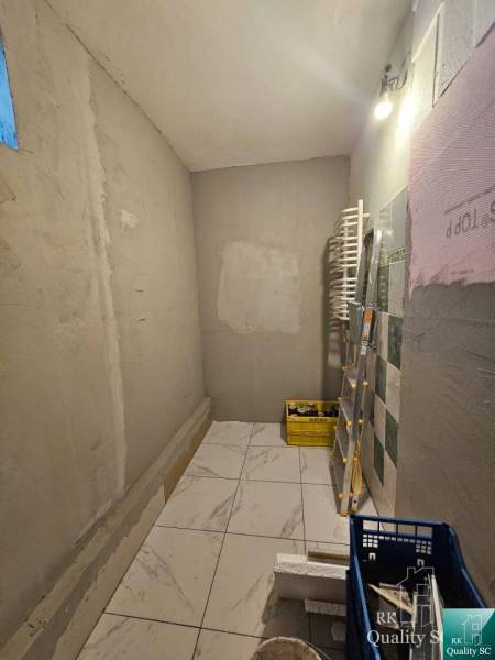 Interior of a family house with tiles, a bucket, a ladder, and construction materials.