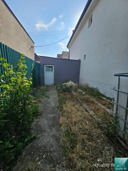 Family house on Rybničná Street in Veľká Mača, narrow yard with greenery and a concrete walkway.