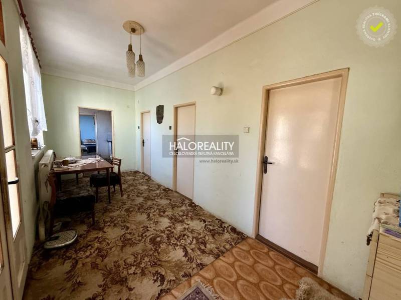 Interior of a family house with a hallway, table, chairs, and carpet.