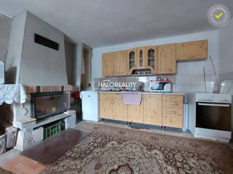 A kitchen with a fireplace and wooden kitchen cabinets in a family house.