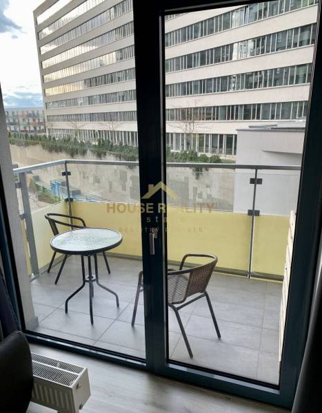 A balcony with furniture in a 2-room apartment overlooking neighboring buildings.