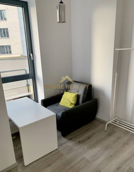 Armchair, table, and stand in a 2-room apartment with a large window and floor.