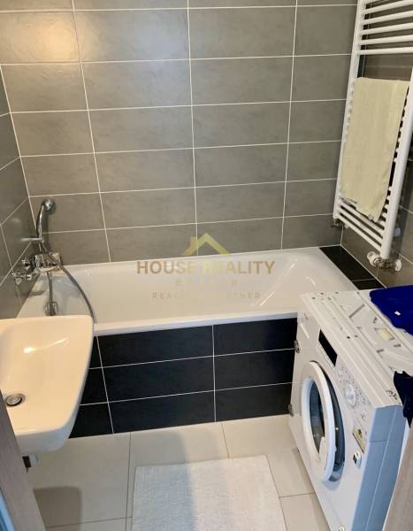 Bathroom with shower, washing machine, and sink in a 2-room apartment.
