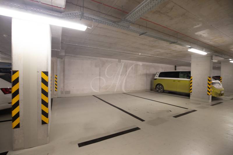 An underground parking lot with concrete walls and columns in the garage. Three parked vehicles.