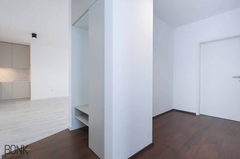 A hallway in a 3-room apartment with a dark floor and light walls.