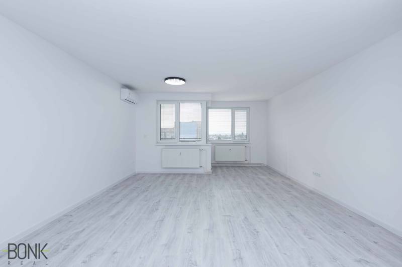 A spacious room in a 3-room apartment with white walls and laminate flooring.
