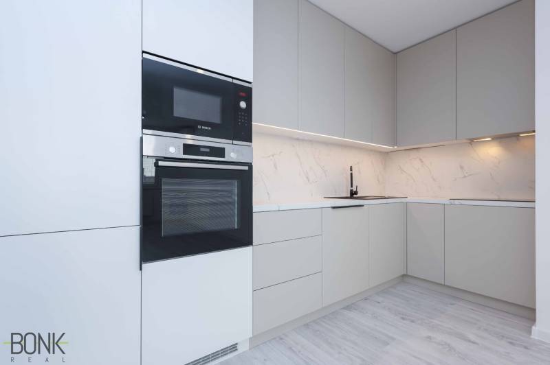 A kitchen in a family house with white cabinets, a stove, and marble tiles.