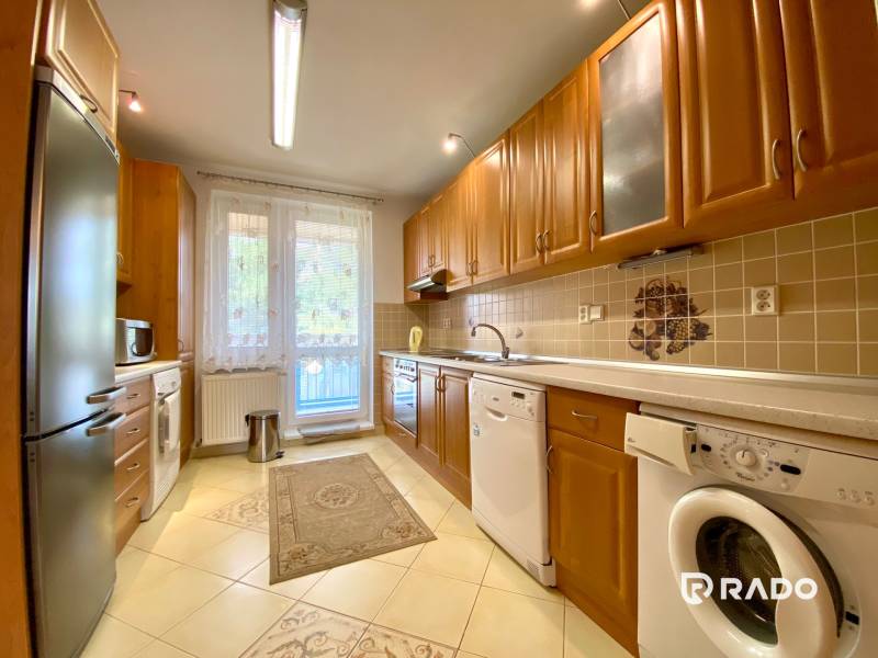 A spacious kitchen in a 3-room apartment with wooden cabinets and appliances.