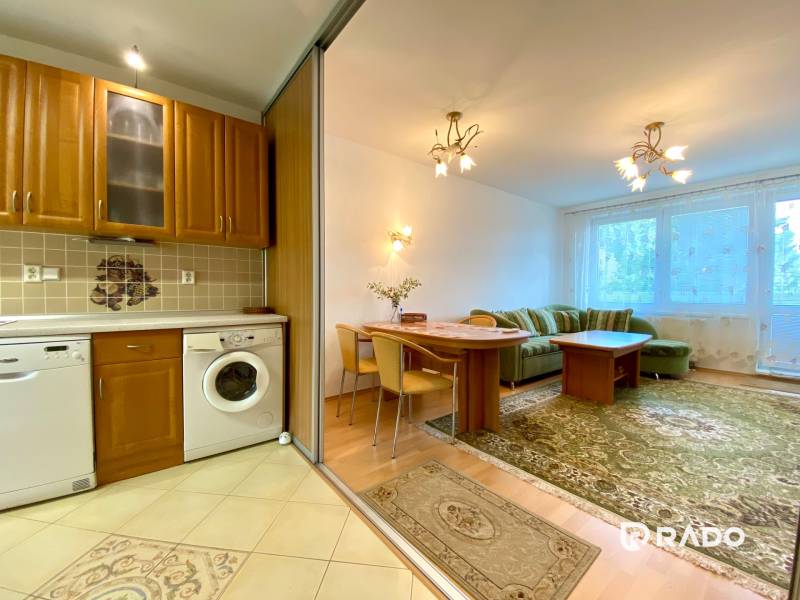 A kitchen with wooden furniture, a living area with a sofa in a 3-room apartment.