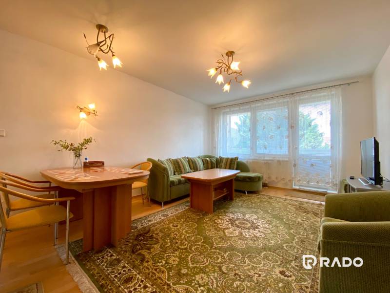 Spacious living room with a green carpet and a sofa in a 3-room apartment.