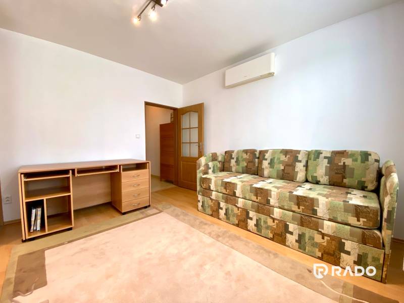 Living room in a three-room apartment with a sofa bed and a wooden desk.