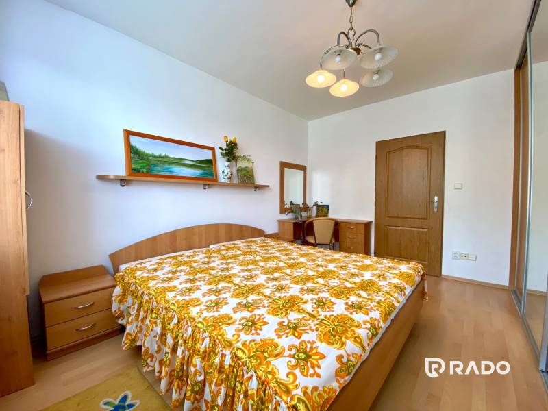 A bedroom in a 3-room apartment, with wooden furniture and a striking floral bedspread.