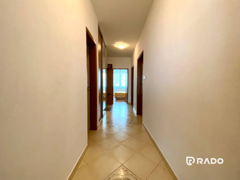 A corridor with a tiled floor in a 3-room apartment, leading to a sunny room.