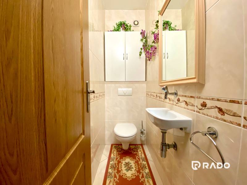 Bathroom with a mirror, sink, and wooden door in a 3-room apartment.
