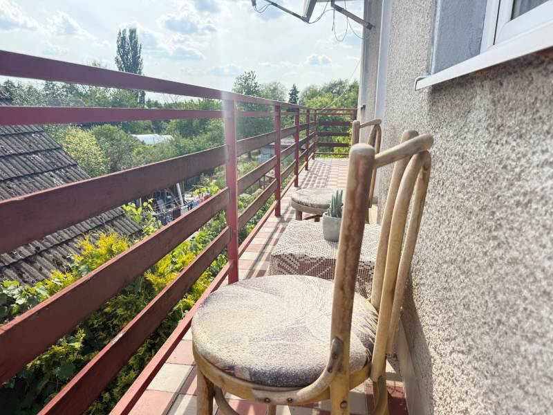 Balkón rodinného domu v Skačanoch s drevenými stoličkami a výhľadom na záhradu.