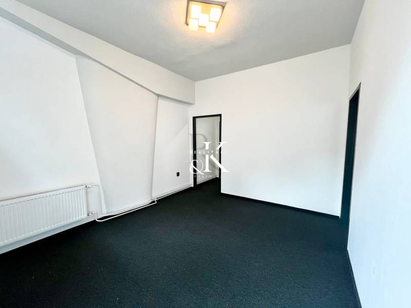 Commercial premises with white walls, dark flooring, and a radiator located in the interior.