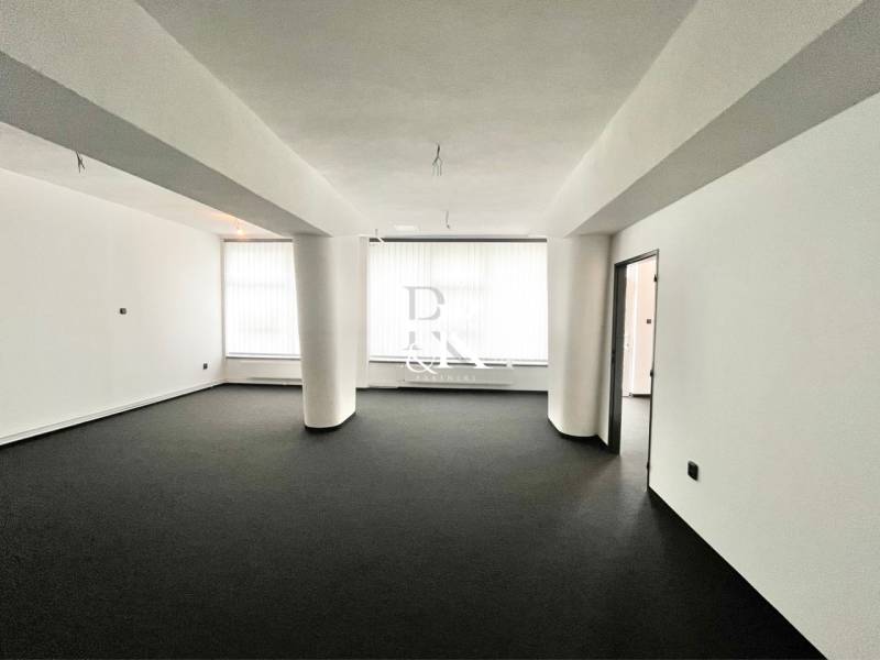 Spacious commercial premises with black carpet and white walls, unfurnished.