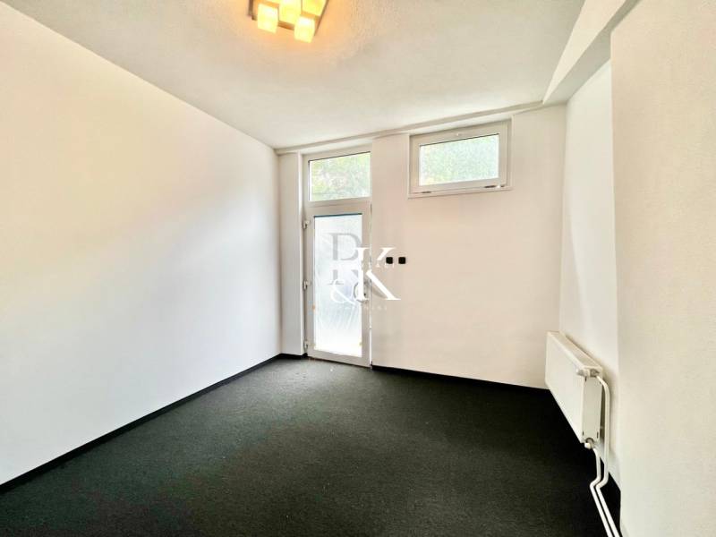 Interior of a commercial space with black carpet, white walls, and glass doors.