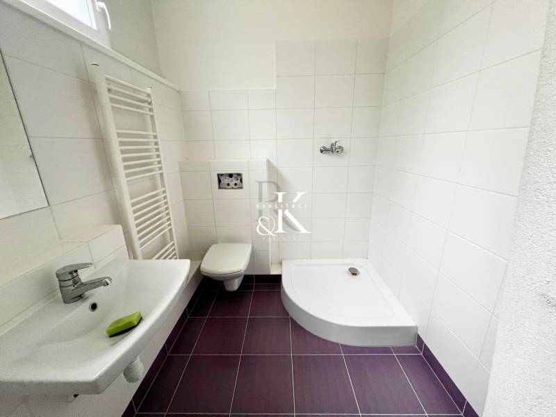 A bathroom with white tiles and purple flooring in commercial premises.