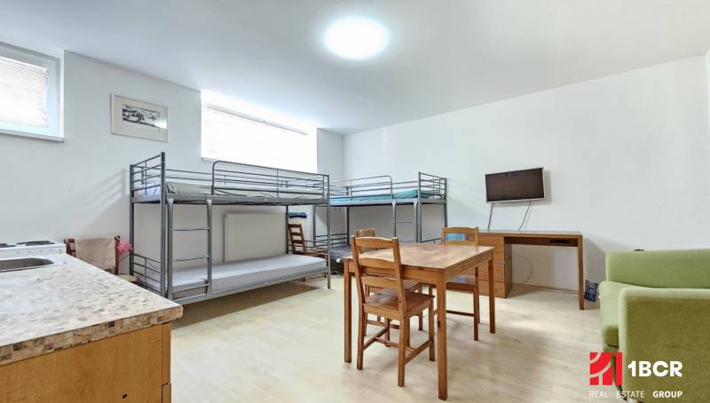 A room in a one-room apartment with bunk beds, a table, and a television.