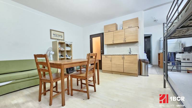 Kitchen unit, dining table, and bunk bed in a studio apartment.