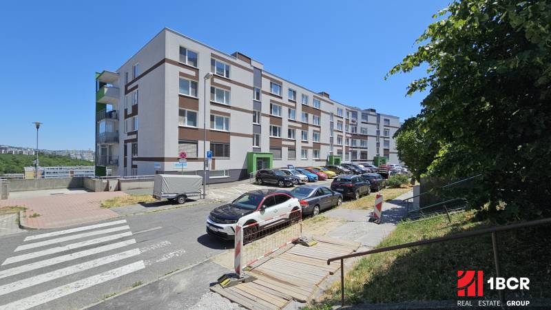 Apartment building on Jána Stanislava in Bratislava - Karlova Ves, parking lot and cars along the sidewalk.