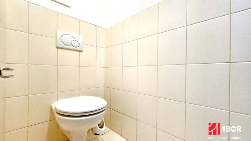 A toilet with ceramic tiles in a one-room apartment.