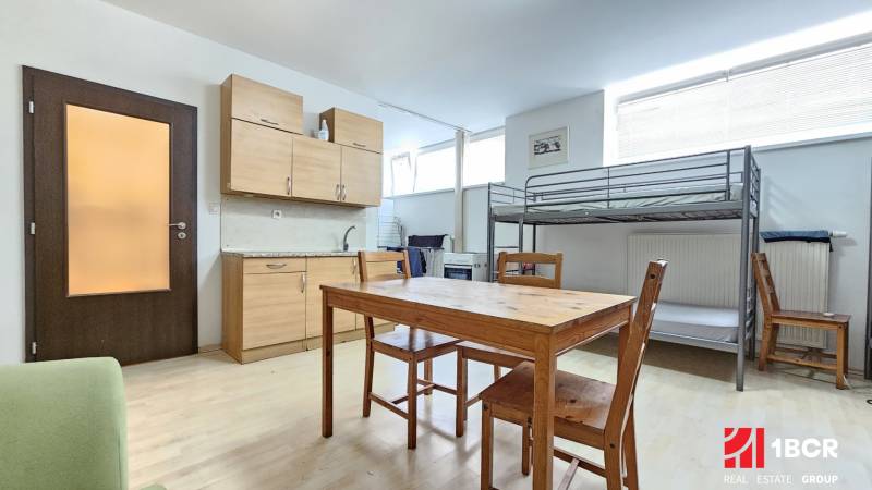 Kitchen unit and bunk bed in a studio apartment with a dining table and chairs.