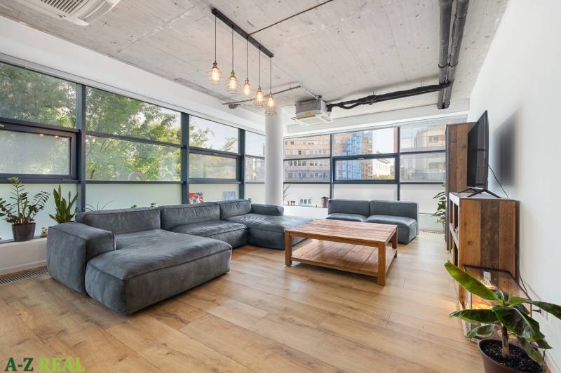 Bright living room in a 4-room apartment with a large gray couch and a wooden table.