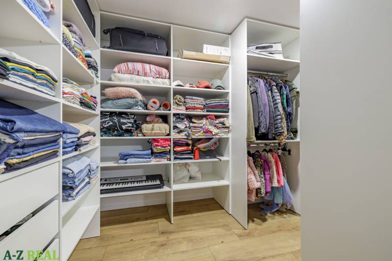 A wardrobe with a set of clothes and accessories in a 4-room apartment, light wooden floors.