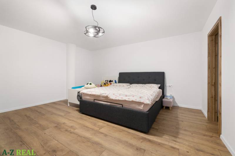 A bedroom with a gray bed, wooden floor, and children's toys in a 4-room apartment.