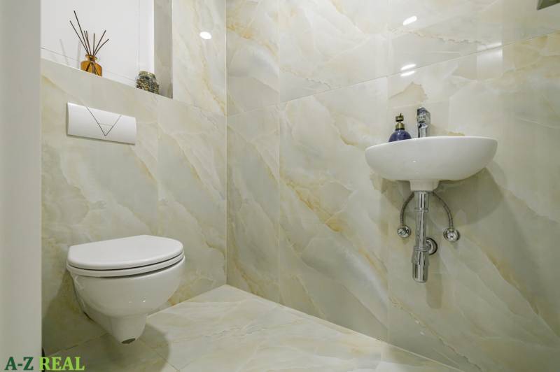A toilet in a 4-room apartment with floral accessories and a light fixture.