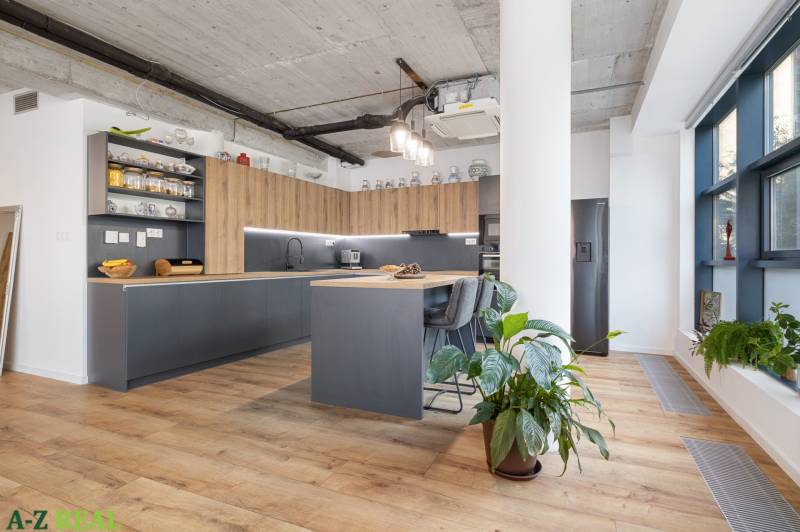 Spacious kitchen with wooden flooring in a 4-room apartment, live plants, and modern equipment.