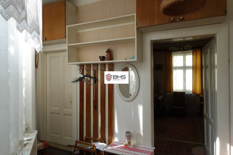 Interior of a family house with coat racks, a mirror, and a window with curtains.
