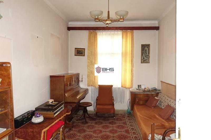 A room in a family house with a piano, brown furniture, and curtains.