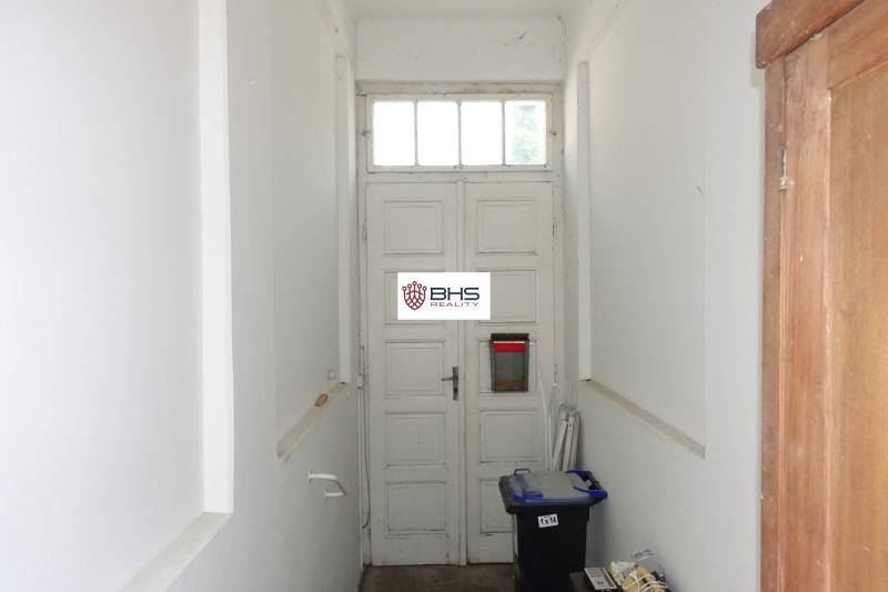 A hallway in a family house with old wooden doors and boxes on the floor.