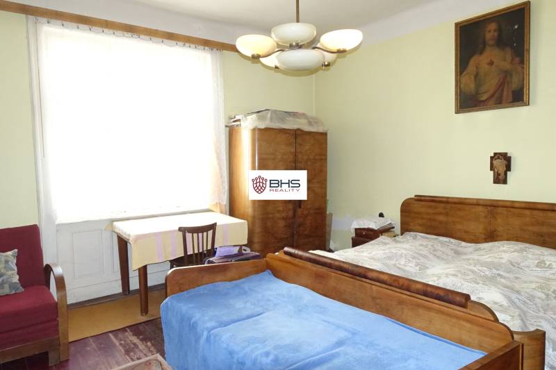 A bedroom in a family house with wooden furniture, a painting, and a chandelier.