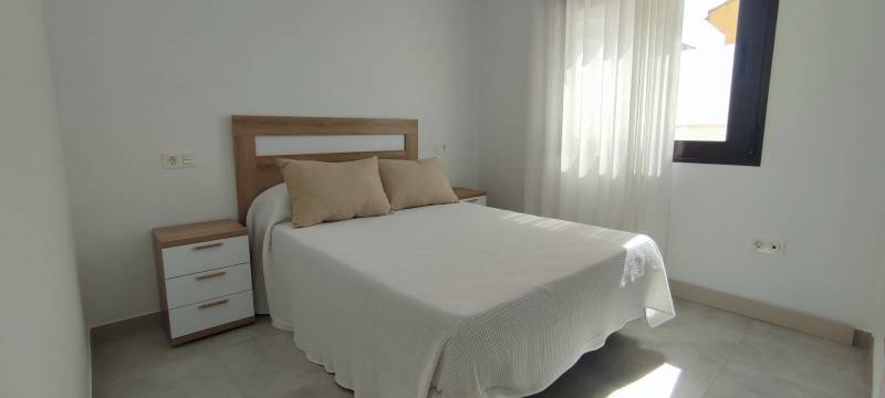 Bright bedroom with curtains, a double bed, and a nightstand in a 4-room apartment.