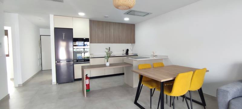 A kitchen in a 4-room apartment with a dining table and yellow chairs.