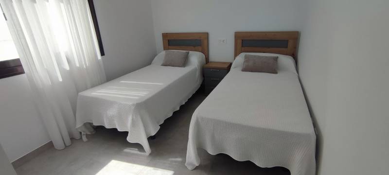 Two single beds with a nightstand and tasteful decorative pillows in a four-room apartment.