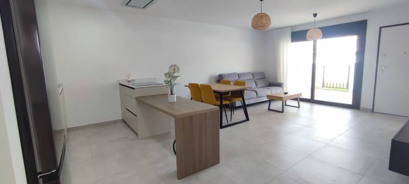 Interior of a 4-room apartment with a refrigerator, kitchen island, dining table, and sofa.