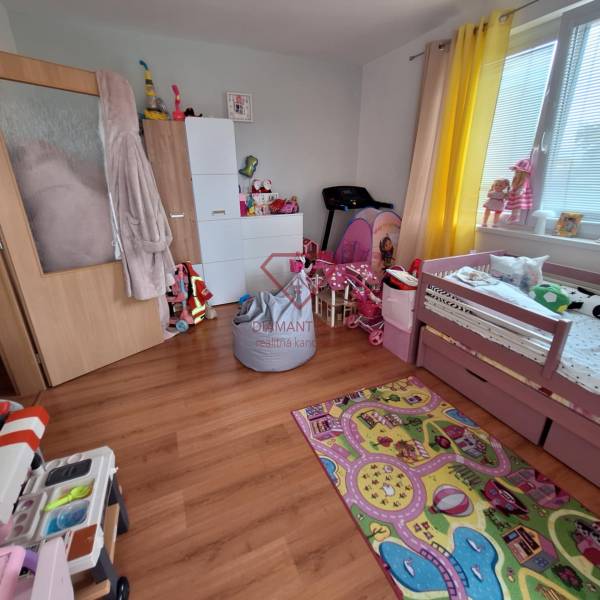 Children's room in a 3-room apartment with a bed, toys, and a colorful carpet.