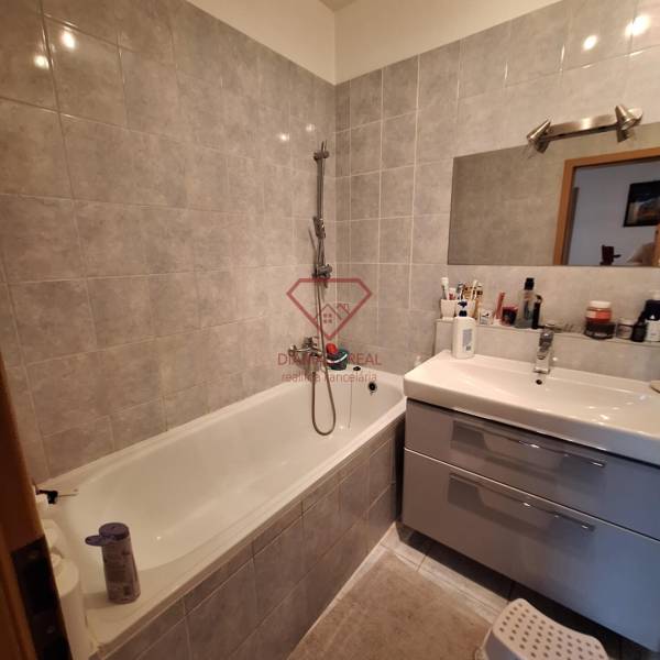 A bathroom in a 3-room apartment with a bathtub, sink, and gray tiles.