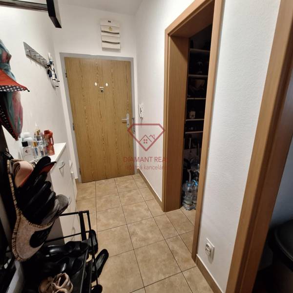 A hallway with a shoe rack and a coat rack in a 3-room apartment, tiled floor.
