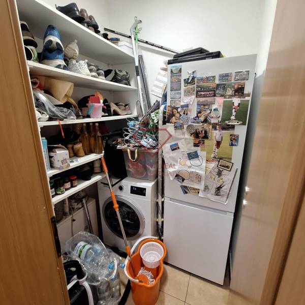 Pantry in a 3-room apartment with a washing machine, refrigerator, and shelves full of items.