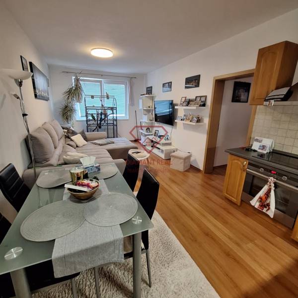 Kitchen corner and living room in a 3-room apartment with a table, sofa, and television.